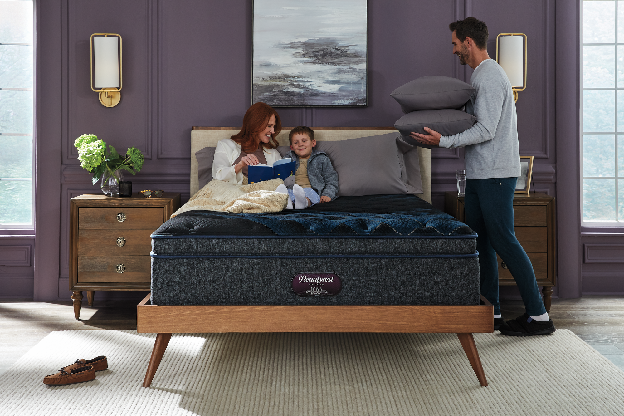 A mother reading to her daughter comfortably in a Beautrest adjustable bed with the Dad bringing breakfast